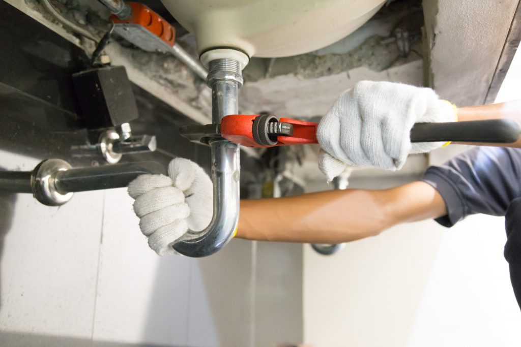 Plumber Fixing White Sink Pipe With Adjustable Wrench 1